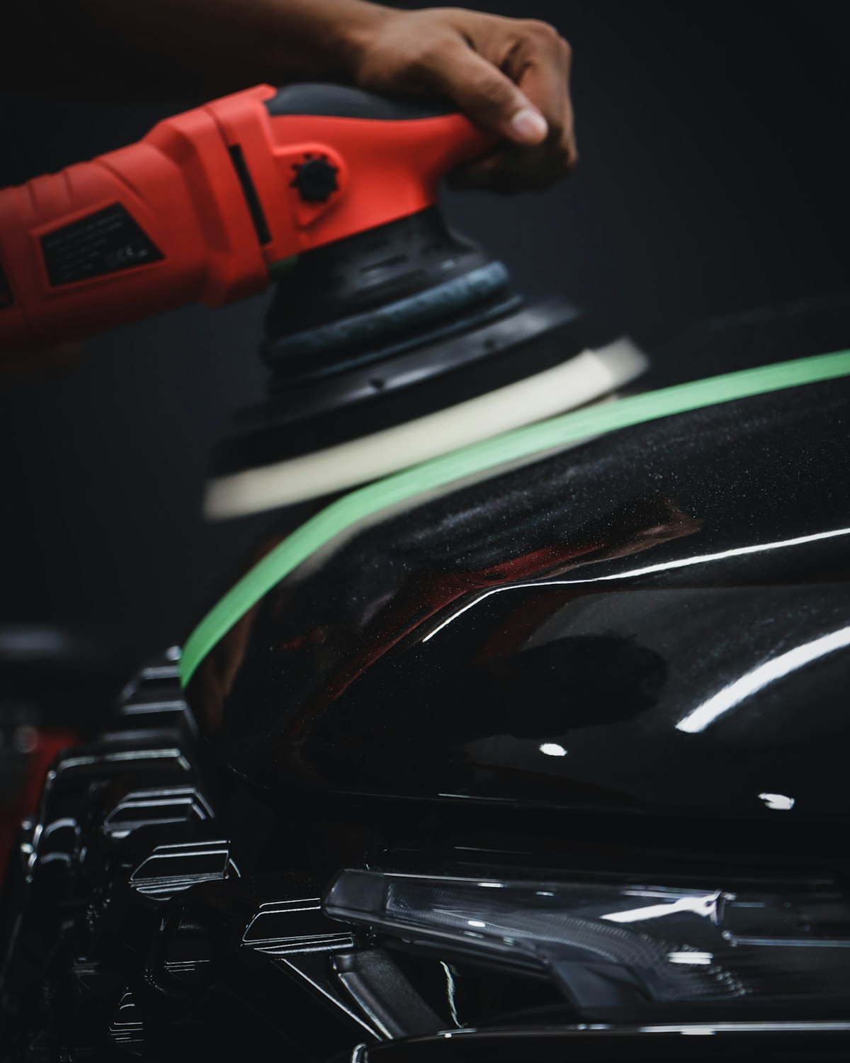 A detailer polishing a car's headlight with a buffer