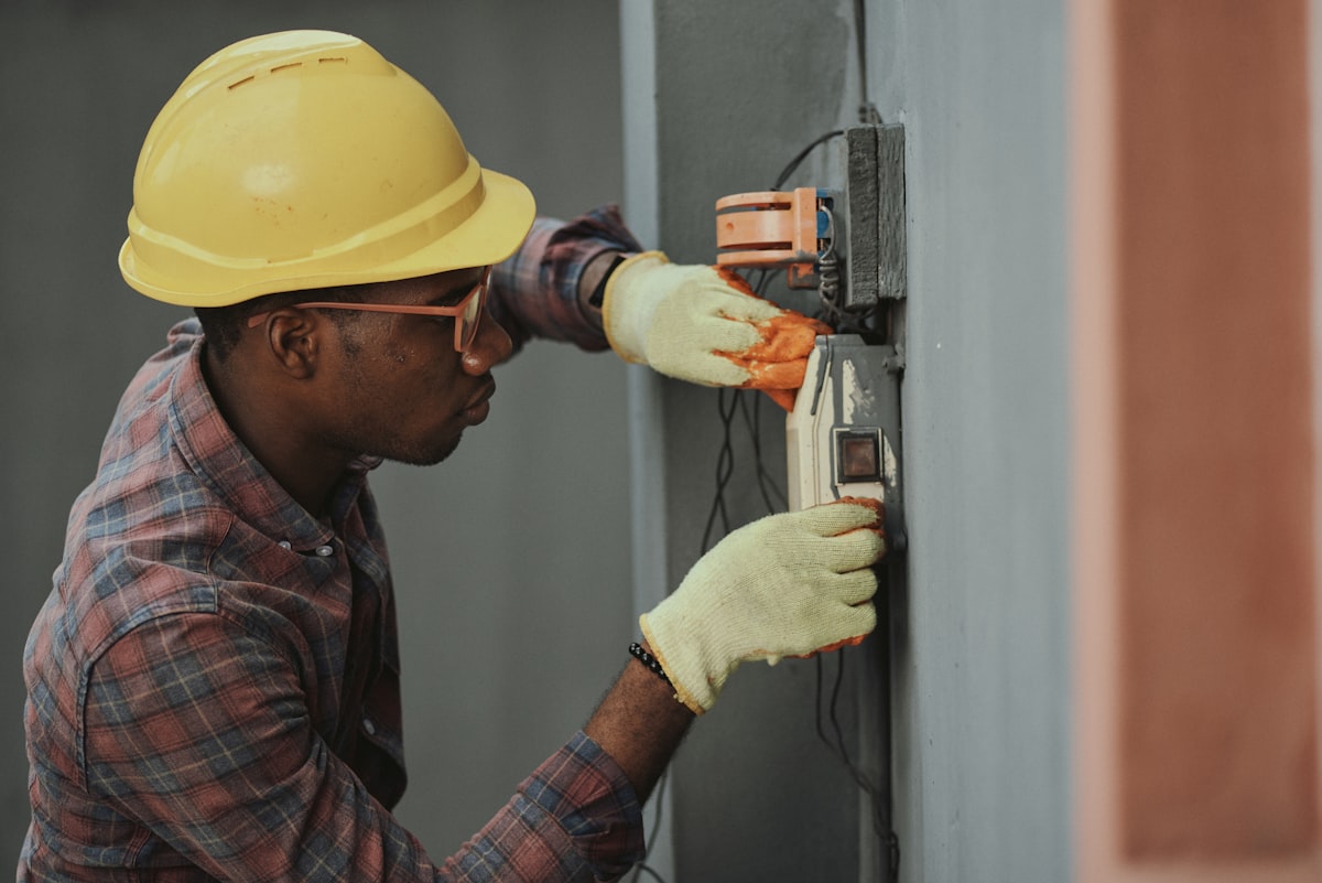 Electrician in a hard hat working on an electrical panel