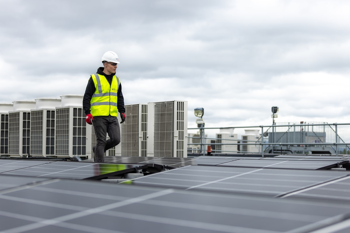 HVAC technician in a hard hat walking among rooftop units