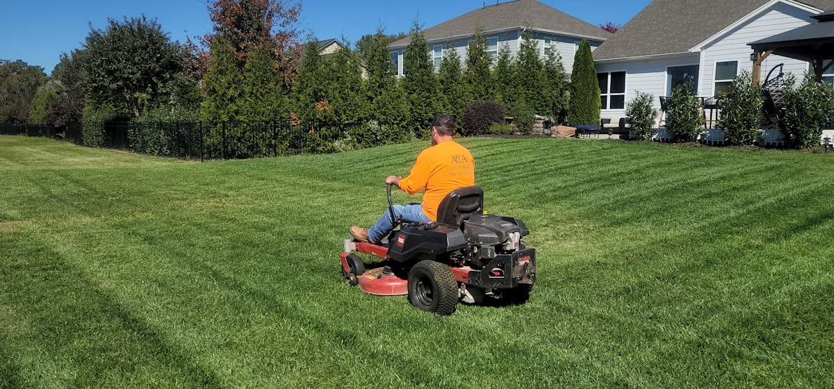 Lawn care worker mowing a lawn on a riding mower