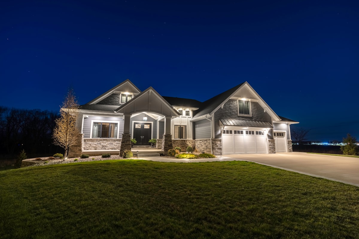 A house exterior illuminated by warm outdoor landscape lighting at night