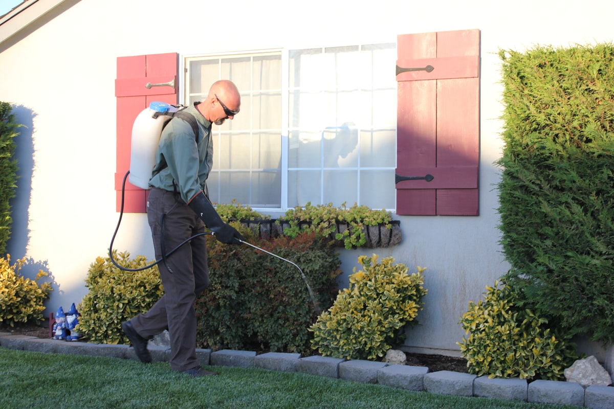 Pest control technician spraying the exterior of a home