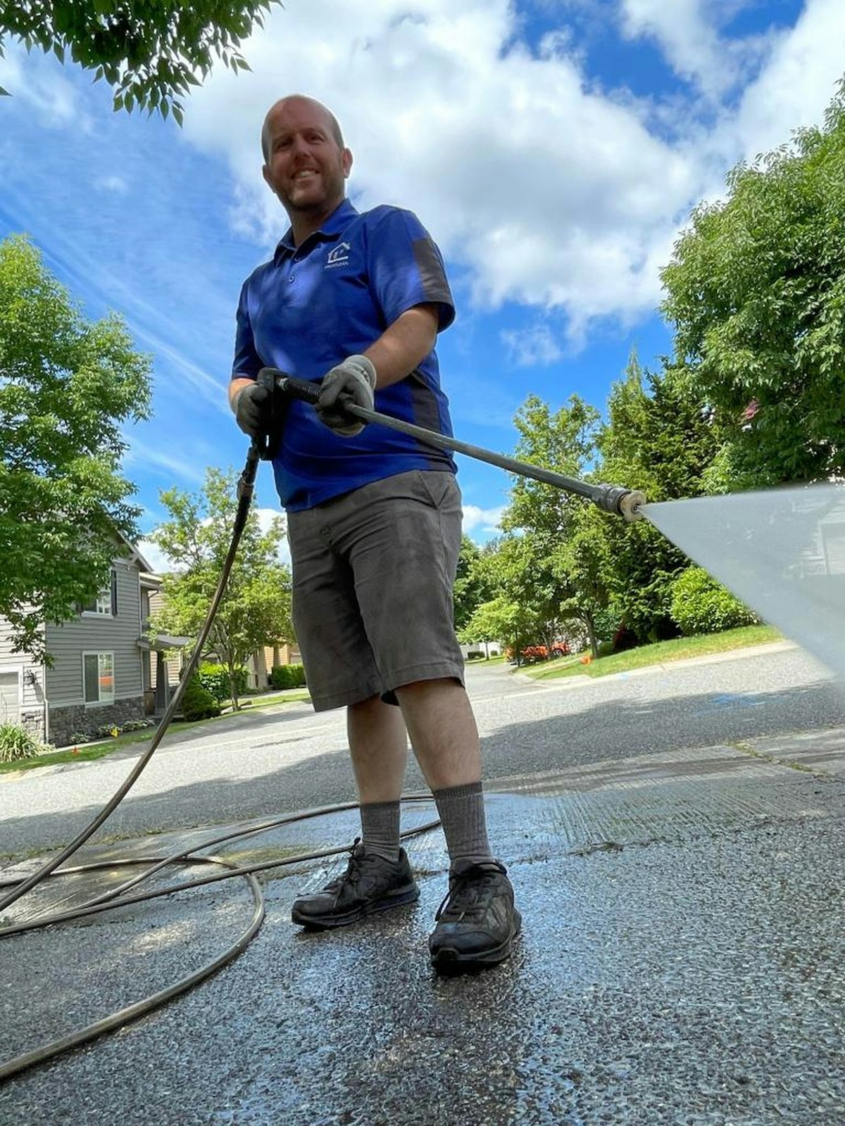 Man pressure washing a concrete driveway with a hose