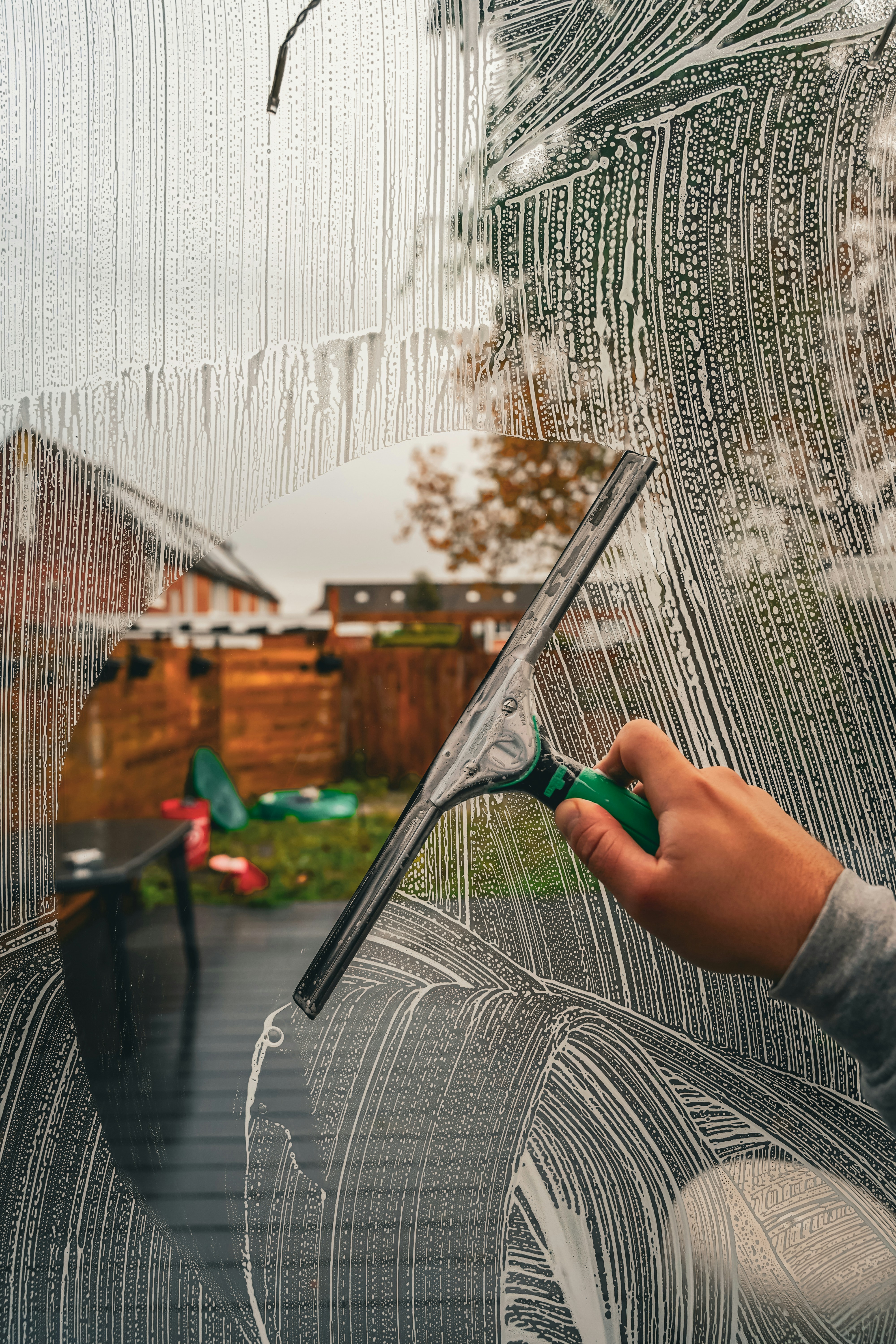 Person using a squeegee to clean a glass window